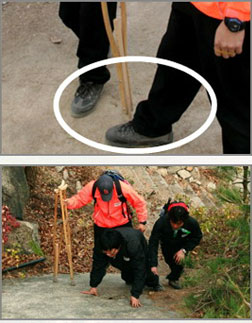 보조자가 목발사용자를 보조하는 모습, 경사가 있는 곳에서 손걸음으로 등산하는 모습
